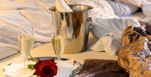 A Silver Pot And Wine Glasses On A Bed